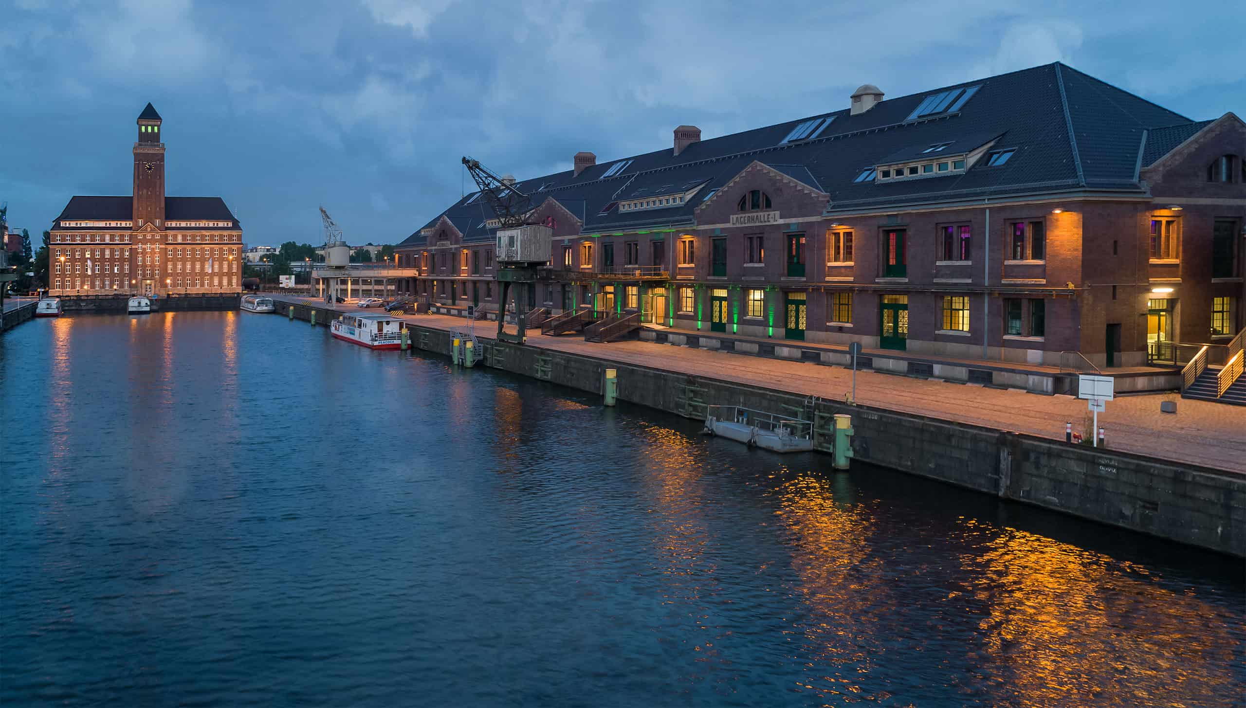 Ein Bild, das das malerische Ambiente des WECC einfängt, gelegen entlang des Westhafens, welcher die architektonische Schönheit der Stadt und ihre Wassermerkmale hervorhebt.