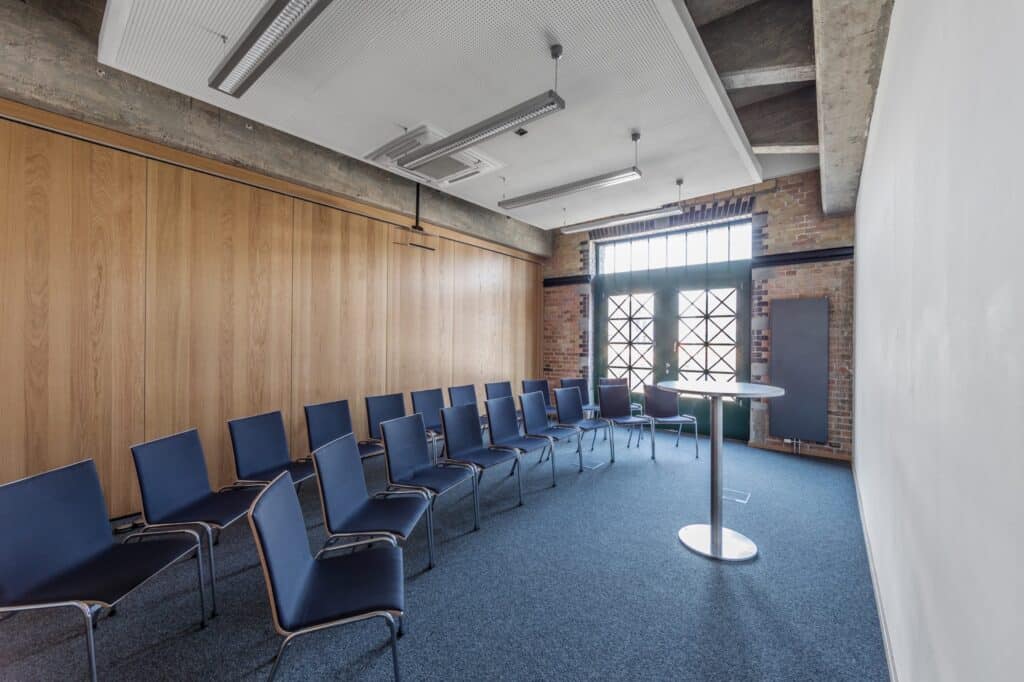 Ein gut eingerichteter Besprechungsraum mit bequemen Stühlen, die um einen Projektor angeordnet sind, bereit für professionelle Präsentationen.