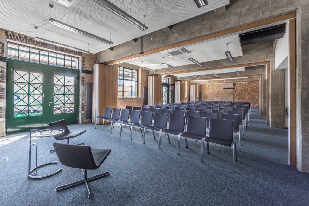 Ein geräumiger Raum mit mehreren Stühlen und einer grünen Tür im Hintergrund, der eine ruhige Atmosphäre für Konferenzen schafft